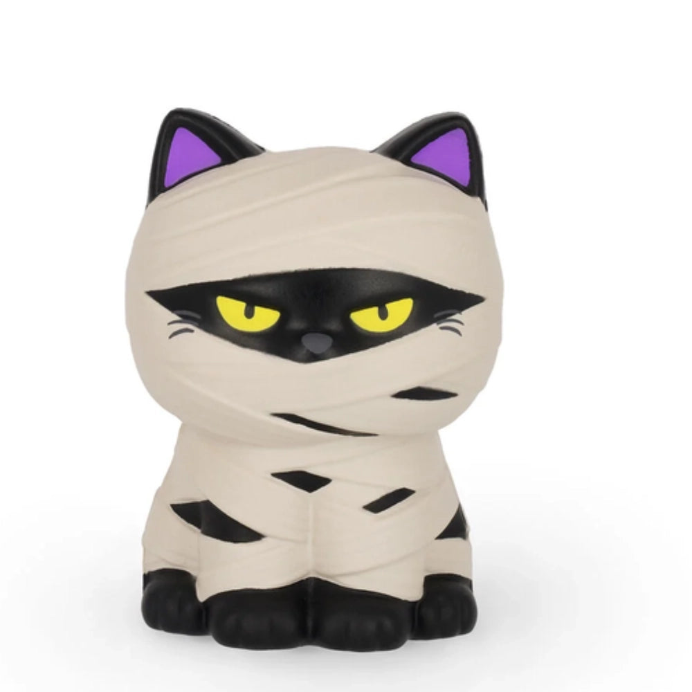 Legami Antistress Kitty Mummy lifestyle Halloween: gatto mummia squishy su tavolo con bara viola zucca arancio e ragno nero