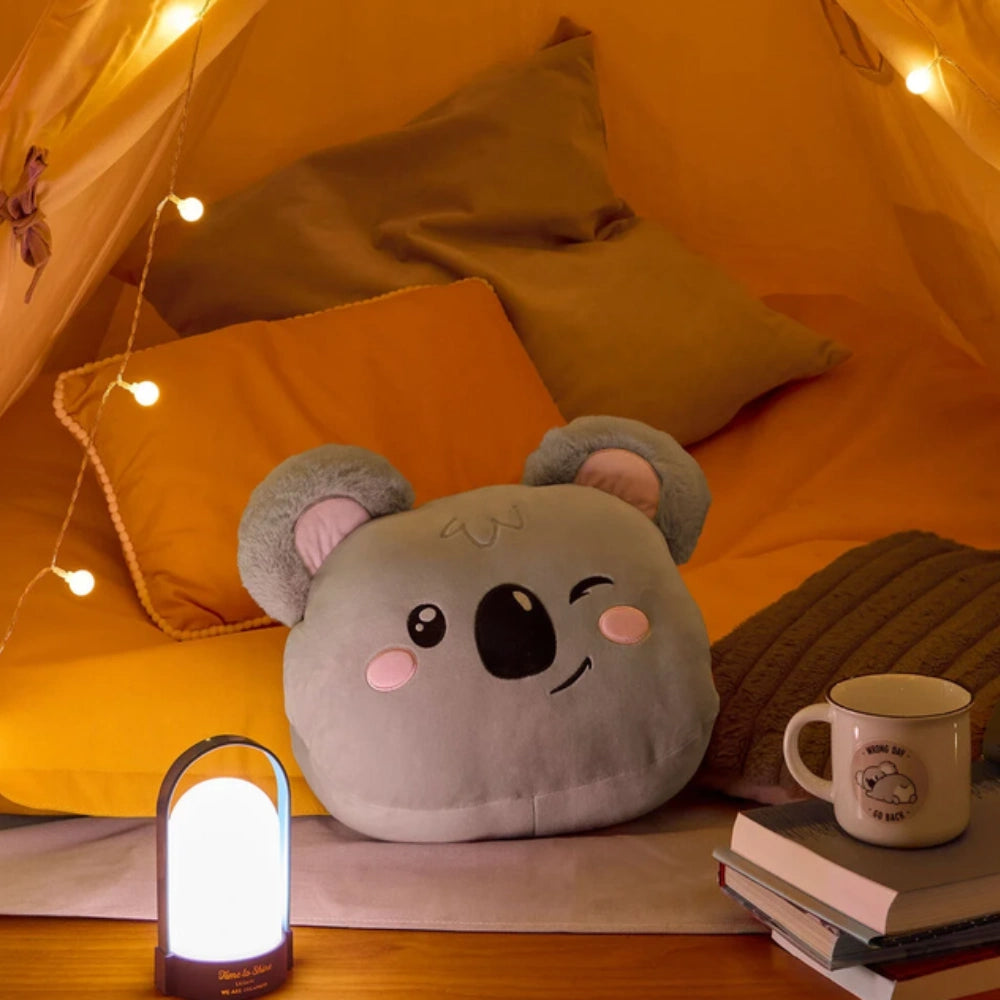 Cuscino Koala Legami ambientato in un angolo lettura con luci e libri